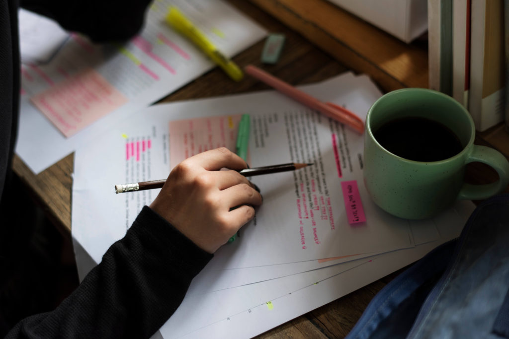 Organize into Groups. Woman organizes brain dump into categories. Cup of coffee sits nearby.